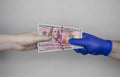 Hand in glove holds dollars with germs. The concept of dirty money as a carrier of bacteria and viruses