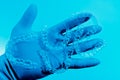 Hand in glove holds invisible dental braces on blue background. Plastic braces dentistry retainers to straighten teeth