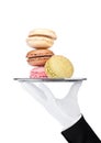 Hand with glove holds tray with sweet macarons