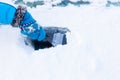 Hand in glove with ice scraper scratching snow from windshield