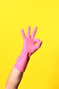 Hand with glove and ok sign on yellow background