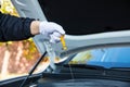 Hand with glove pulling a car`s dipstick to check engine oil level