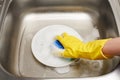 Hand in glove washing plate with blue cleaning sponge Royalty Free Stock Photo