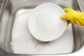 Hand in glove washing plate under running tap water Royalty Free Stock Photo