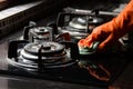 Hand in gloves Cleaning a gas stove at kitchen