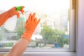 Hand in gloves cleaning window with rag and cleanser spray at ho Royalty Free Stock Photo