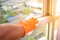 Hand in gloves cleaning window with rag and cleanser spray at ho Royalty Free Stock Photo