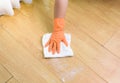 Hand in gloves cleaning Wooden floor with rag and cleanser at