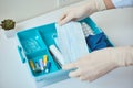 Hand in gloves take protective midicine mask from first aid kit. Home medicine box with a medical items. Virus protect concept Royalty Free Stock Photo