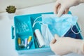 Hand in gloves take protective midicine mask from first aid kit. Home medicine box with a medical items. Virus protect concept Royalty Free Stock Photo