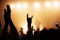 hand with a goat sign of dancing punk from the crowd at a cool band rock concert. silhouette of a musician on stage in a haze. mus