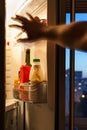 Hand goes for food in refrigerator in eveving Royalty Free Stock Photo
