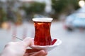 Hand golding strong black tea in traditional turkish glass cup on plate outdoors.Street dring in Turkey concept.Copy Royalty Free Stock Photo