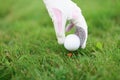 Hand in golf glove puts ball on golf tee Royalty Free Stock Photo