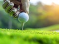 Hand in golf glove putting golf ball on tee in golf course for healthy sport Royalty Free Stock Photo