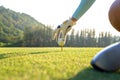 Hand golfer woman putting golf ball on tee with club in golf course on evening time for healthy sport. Royalty Free Stock Photo