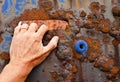 Hand grabbing on to a rusting panel from a boat.