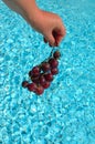 Hand with grapes over water Royalty Free Stock Photo