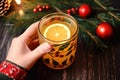 a hand grasping a hot toddy mug decorated with holly