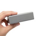 A hand grasping a sleek, rectangular, silver metallic object against a white background Royalty Free Stock Photo