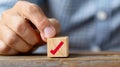 A hand grasps a wooden cube representing a checklist, symbolizing assessment and quality control in survey processes