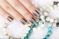 Hand with gray metallic manicured nails and colorful bracelets