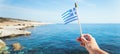 Hand with Greek waving flag flying over sea water Royalty Free Stock Photo