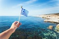 Hand with Greek waving flag flying over sea water Royalty Free Stock Photo