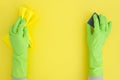 Hand in green cleaning rubber glove with sponge on yellow background. Royalty Free Stock Photo