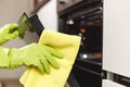 Hand in Green Glove Cleaning Kitchen Oven Door with Microfiber Rag. Doing Home Chores Royalty Free Stock Photo
