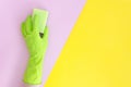 Hand in green glove with sponge on yellow pink bright split color background. Flat lay copy space vibrant duotone Royalty Free Stock Photo