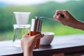 Hand grinding coffee beans with manual stainless steel grinder to make drip coffee Royalty Free Stock Photo