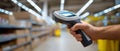 Close-up of hand holding barcode scanner in warehouse aisle with shelves and boxes in background under bright lighting Royalty Free Stock Photo