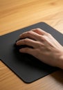 A hand gripping a black computer mouse rests on a black mouse pad. The surface Royalty Free Stock Photo