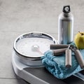 Hand grips, aluminium flask and apple on gym floor, copyspace Royalty Free Stock Photo