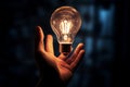 Hand grips a glowing white light bulb, a symbol of creativity Royalty Free Stock Photo