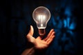 Hand grips a glowing white light bulb, a symbol of creativity Royalty Free Stock Photo