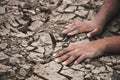 Hand on ground cracked dry due to drought.