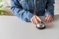 Hand of guest in a denim jacket ringing in silver bell. reception desk with copy space. Hotel service. Royalty Free Stock Photo