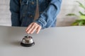 Hand of guest in a denim jacket ringing in silver bell. reception desk with copy space. Hotel service. Royalty Free Stock Photo