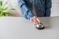 Hand of guest in a denim jacket ringing in silver bell. reception desk with copy space. Hotel service. Royalty Free Stock Photo