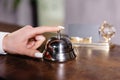 Hand of guest ringing bell on reception desk of in hotel