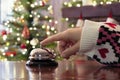 Hand of guest ringing reception bell on desk of guesthouse, hotel at christmas time. Color shining garland on christmas tree