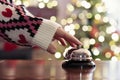 Hand of guest ringing reception bell on desk of guesthouse, hotel at christmas time. Color shining garland on christmas tree Royalty Free Stock Photo