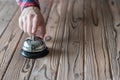 Hand of guest ringing silver vintage bell on wooden rustic reception desk with copy space. Hotel, restaurant. Royalty Free Stock Photo