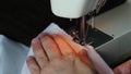 Hand guiding cloth through sewing machine