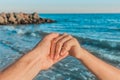 The hand of the guy holds a close-up of the girl`s hand against the sea as the sunset approaches. Symbol of relationship concept