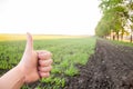 A man holds a thumbs up against the background of a green field.