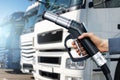 Hand with H2 nozzle on a background of hydrogen fuel cell semi trucks. Royalty Free Stock Photo