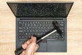 Hand with a hammer and laptop with a broken screen